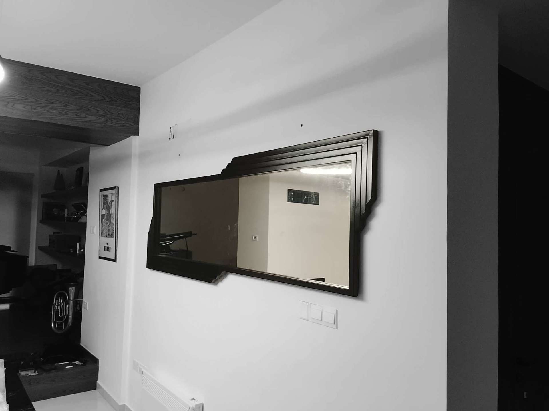 Wall-mounted mirror in a custom stepped dark metal frame