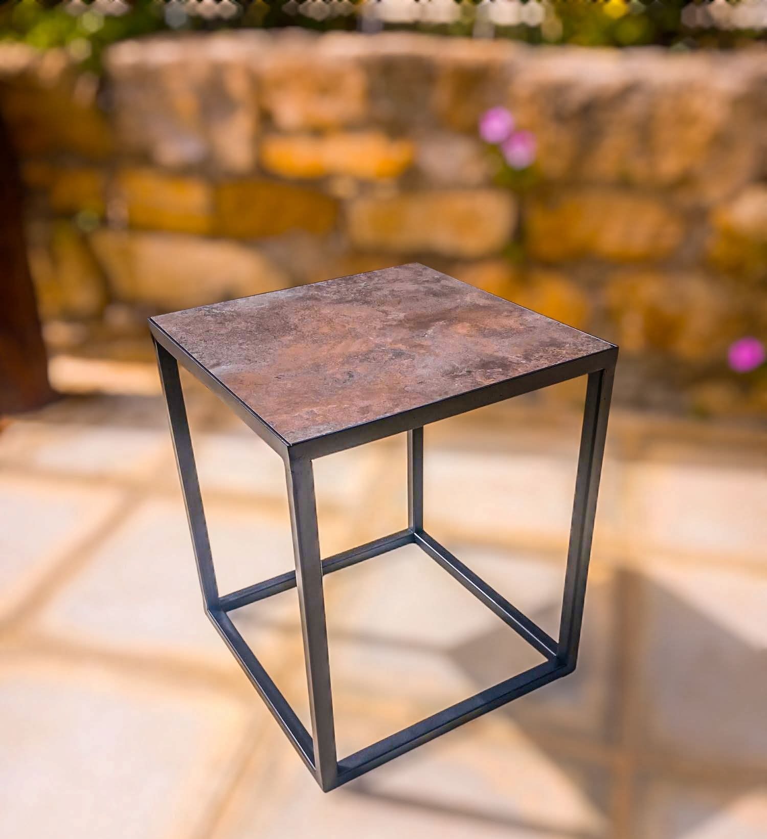 Steel cube side table with natural stone top in a courtyard